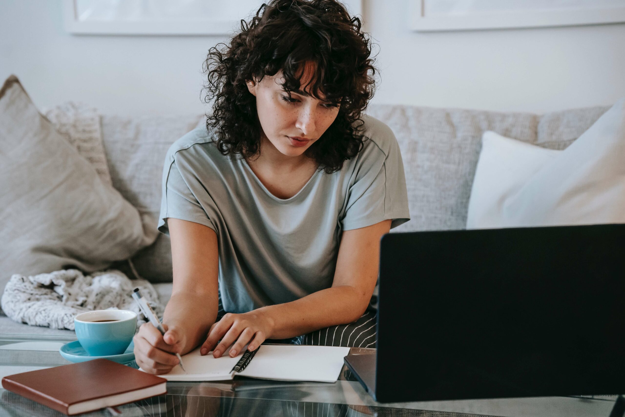 woman writing and using laptop